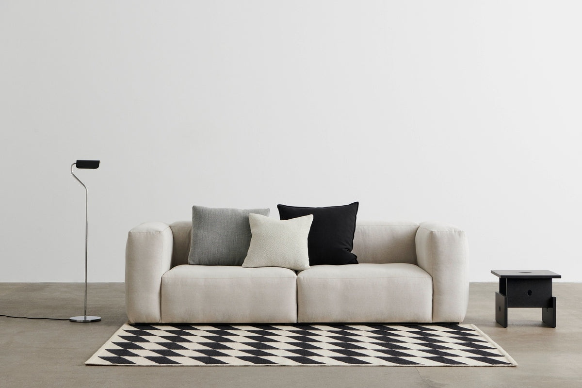 HAY sofa, rug and floor lamp arranged in a softly lit living room.