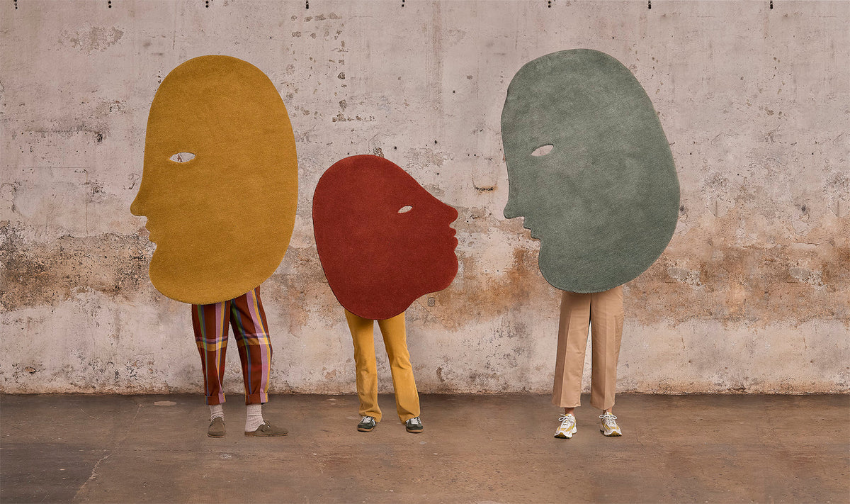 Three people holding Jaime Hayon Talk Talk rugs by Nanimarquina.
